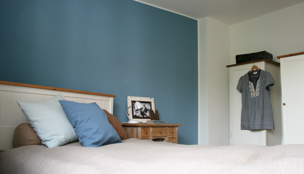 Weisses Bett und Kleiderschränke vor blauer Wand